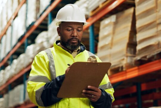 Black man, supervisor and clipboard at warehouse with counting or checklist, stocktake and delivery. Male person, employee and manufacturing for supplier in supply chain, logistics and wholesale.
