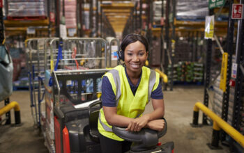Woman leaning on a tow tractor in a distribution warehouse Woman leaning on a tow tractor in a distribution warehouse