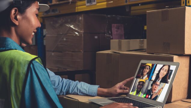 Warehouse staff talking on video call at computer screen in stor